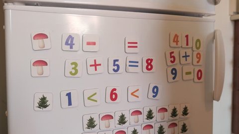 WROCLAW, POLAND - APRILE 01, 2018: Kid plays with Magnets of simple Mathematical Numbers on a Refrigerator