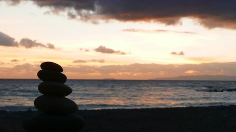 Stone stack on beach and dramatic sunset over sea surface with dark stormy rainy clouds, Greece Peloponnese, time lapse