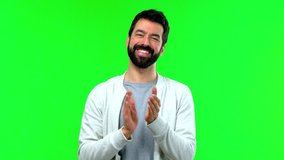 Handsome man with beard smiling and applauding on green screen chroma key