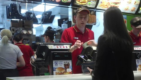 Minsk, Belarus, April 14, 2018: Visitor orders food and pays credit card at McDonald's restaurant