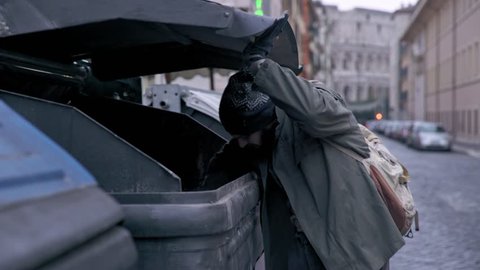 hunger, misery, poverty-bum rummages in the dumpster in the street