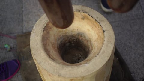 The process of making traditional Thai desserts using large wooden mortars.
