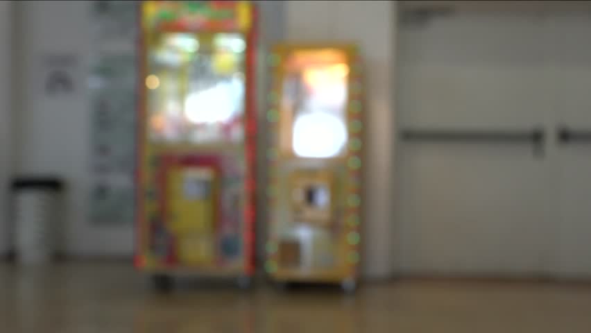 Defocused view of play station(gaming machines) in modern shopping center allowing using a mechanical hand to grab a soft toy as a win