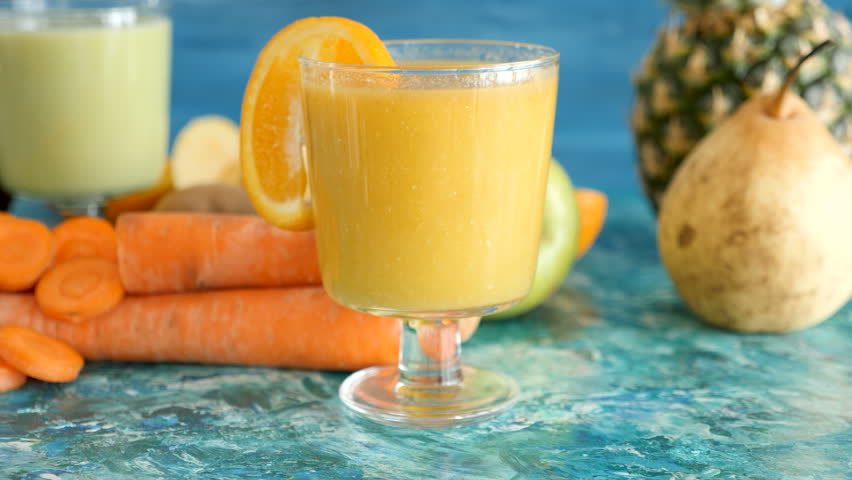 Fresh and organic detox juice next to fruits and vegetables on vivid background