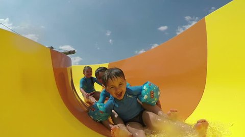 Funny little boys and girls roll with yellow water slides