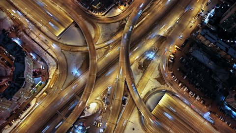 Aerial hyperlapse shooting of a busy multilevel  junction. Illuminated highway from the bird's eye view.  Car light trails at night.