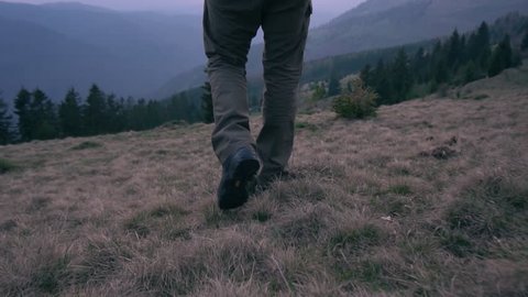 Slow motion:Camera follow hiker's feet on top of the mountain.Close up hiker walking down the valley on sunset.Follow adventurer in magical sunset light on wild mountain.Outdoor activity.Holiday relax