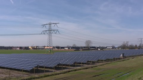 Solar farm and electricity poles servicing a nearby neighbourhood with nZEB buildings (near-zero energy buildings) APELDOORN, THE NETHERLANDS - APRIL 2018