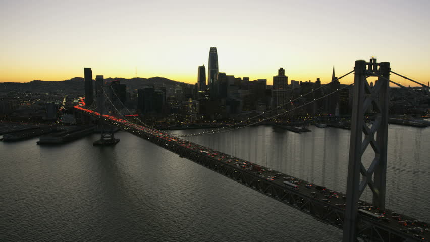 Aerial waterfront night illuminated view of Oakland Bay bridge US 80 Highway commuter traffic skyscrapers San Francisco bay Pacific ocean California USA