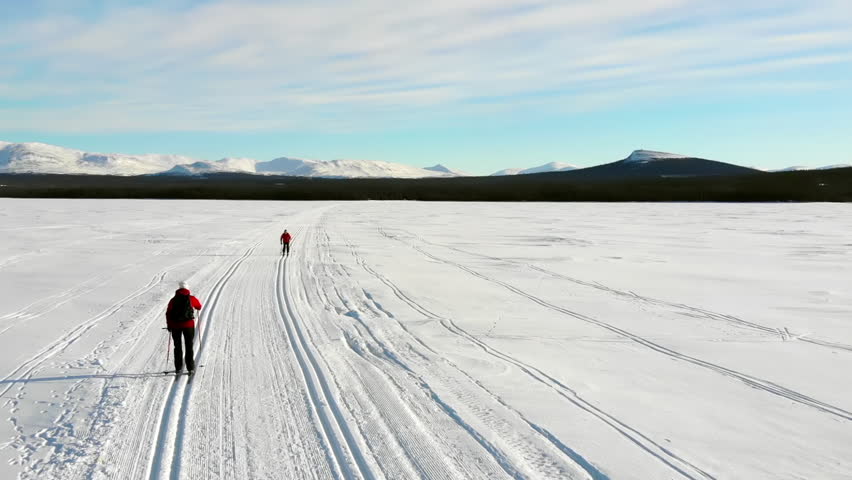 Two women cross country skiing on a lake in the Swedish mountains.