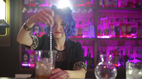 female bartender. girl with blue hair. cocktail making in night bar