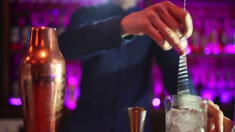 Barman man makes cocktails with a shaker.