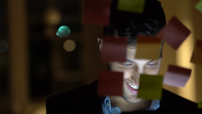 Young man using mobile phone at night in dark office