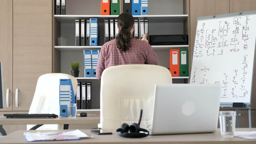 Man entering the office and starts pulling files from the cabinet. He is searching for some documents. Business and finance | Shutterstock HD Video #1009931174