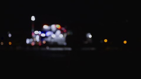 Highway accident with fire trucks and towing truck clearing wreckage, out of focus, night scene