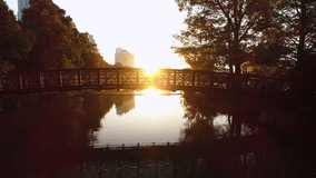 This is an aerial clip of men and women running and walking over a bridge at sunrise in Austin, Texas in the fall.