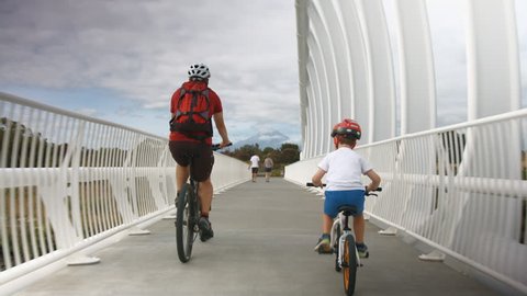 Father and son biking over bridge, Te Rewa Rewa, New Zealand.