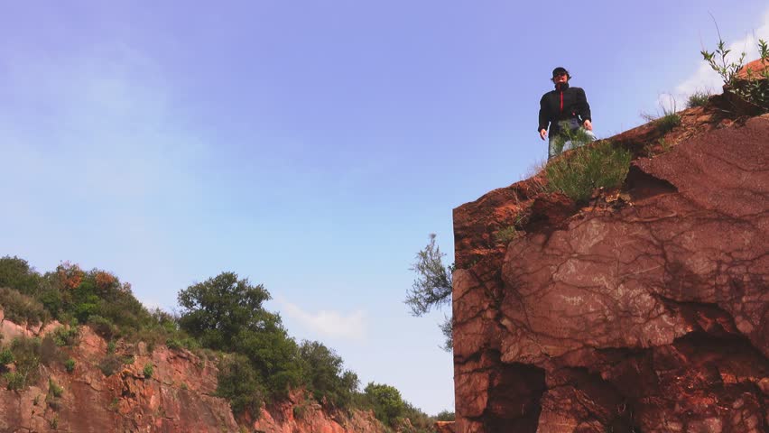 Senior woman going on a cliff edge on the top of mountain with gorgeous view.