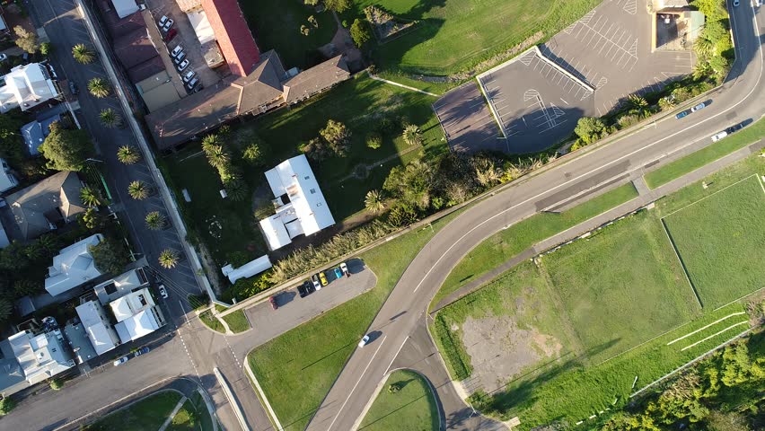 Central part of Newcastle city in NSW of Australia – aerial view over streets, houses, roofs and yards from local park towards distant Nobbys head lighthouse and beach.
