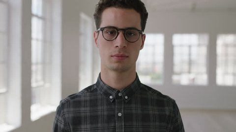 close up portrait of attractive young hipster man looking serious at camera in new apartment wearing glasses real people series