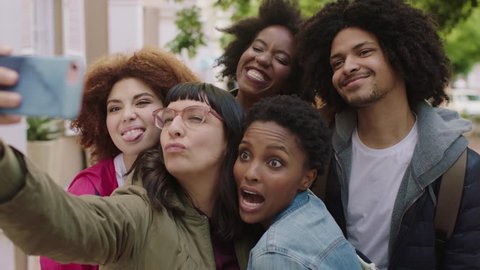 portrait of happy group of multi ethnic friends posing taking selfie photo using smartphone enjoying fun making faces students celebrating vacation together real people series