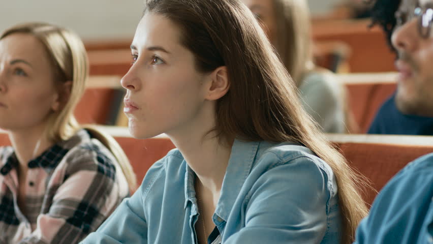 Beautiful and Intelligent Young Girl Listens to a Lecture in a Classroom Full of Multi Ethnic Students. Shallow Depth of Field.  Shot on RED EPIC-W 8K Helium Cinema Camera.