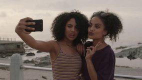 beautiful hispanic twin sisters posing happy taking selfies using phone having fun in seaside background - Powered by Shutterstock - Get 15% off with code: PIKWIZARD15