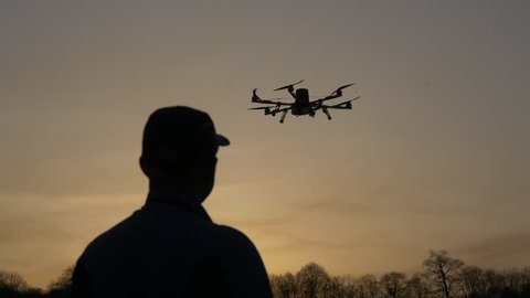 Man silhouette drone control at sunset. Dark silhouette against colorfull sunset. Soft focus