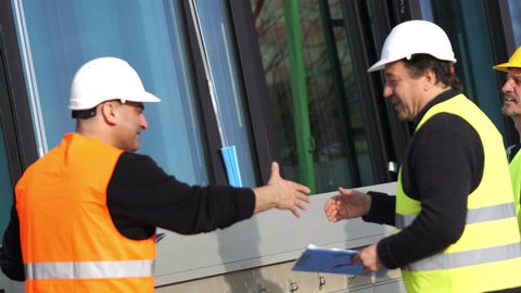 Construction manager and workers shaking hands on construction site
