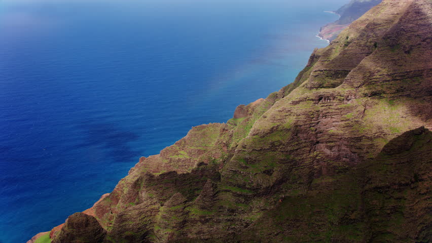 Kauai, Hawaii circa-2018, Aerial view of Na Pali Coast on Kauai with beautiful rugged cliffs and rainbow. Shot from helicopter with Cineflex gimbal and RED Epic-W camera.  Royalty-Free Stock Footage #1009966166