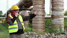 Worker speaks on cell phone at heat electric power station near heating main pipeline. Service engineer talks on smartphone. Master builder in yellow hard hat communicates via mobile phone - Powered by Shutterstock - Get 15% off with code: PIKWIZARD15