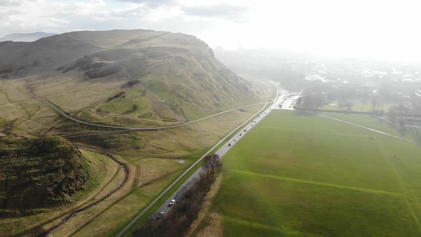 Aerial drone footage cityscape view of The Holyrood Park in cloudy day, Edinburgh, Scotland, United Kingdom. | Shutterstock HD Video #1009972490