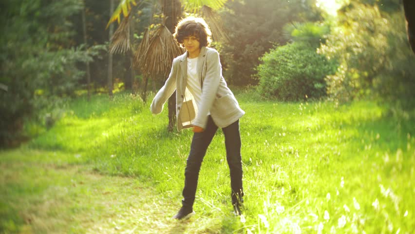 4k. beautiful stylish boy teenager dancing in a city park.