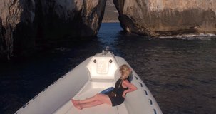 SARDINIA, ITALY – JULY 2016 : Video shot from a boat moving down Porto Flava cave on a sunny day with girl and boat in view