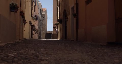 ALGHERO, SARDINIA, ITALY – JULY 2016 : Video shot of beautiful blonde girl walking in narrow street in central Alghero on a sunny day