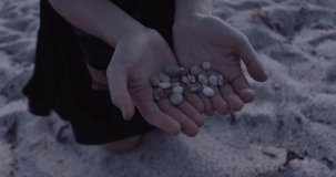 SARDINIA, ITALY – JULY 2016 : Video shot of girl holding tiny rocks on Arutas Beach during beautiful sunset