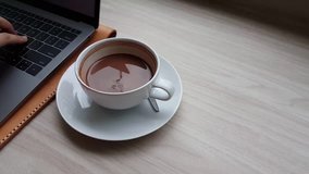 Video clip of a person is typing on laptop with a cup of coffee on the table in the cafe.