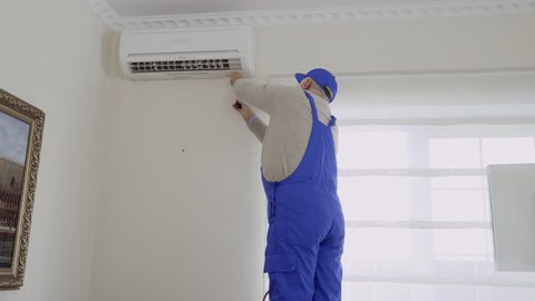 Professional mature master installs the air conditioning in the room