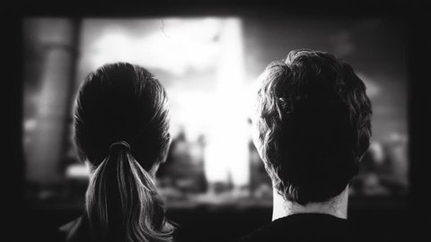 Old Movie Screen Theater Vintage. Couple watching an old movie in a vintage theater. Black and white shot behind model shoulders.: film stockowy