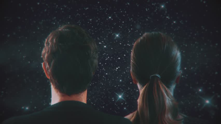 Staring Into Space. Man and a woman looking at the starry sky at night. Shot behind model shoulders.