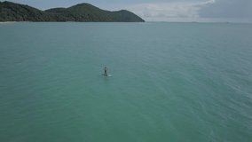 Drone view aerial view of young woman on stand up paddle on sea, tropical climate in Thailand, sport and recreation people concept. Shot in 4K resolution travel vacations enjoyment