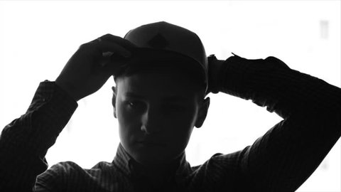 Young man putting on a baseball cap. Monochrome picture of a young man putting on baseball cap and then looking out the window. Slow motion, sketch, isolated.
