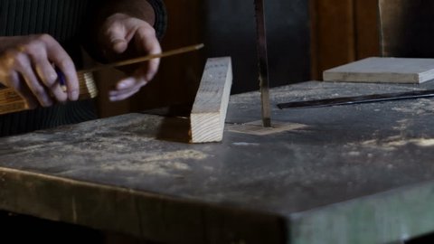 Carpenter measures and marks cutting line using a carpenter's ruler