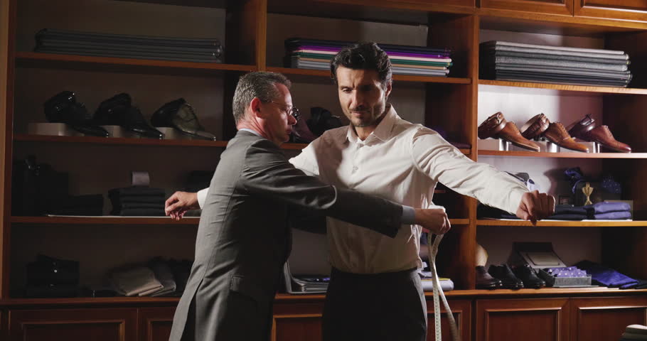 Portarit of a tailor while making a business suit using the tape measure. Concept: Fashion, tailoring, shop