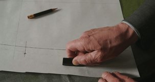A tailor drawing and cutting a cloth according to the tradition of tailors. The dressmaker uses perfectly needle and thread to sew traditional concept, sewing