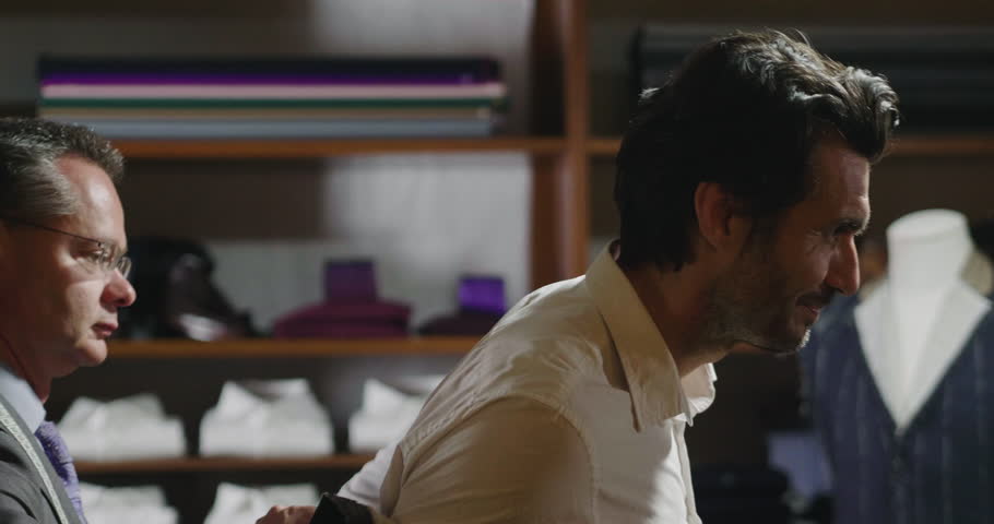 Portarit of a tailor while making a business suit using the tape measure. Concept: Fashion, tailoring, shop