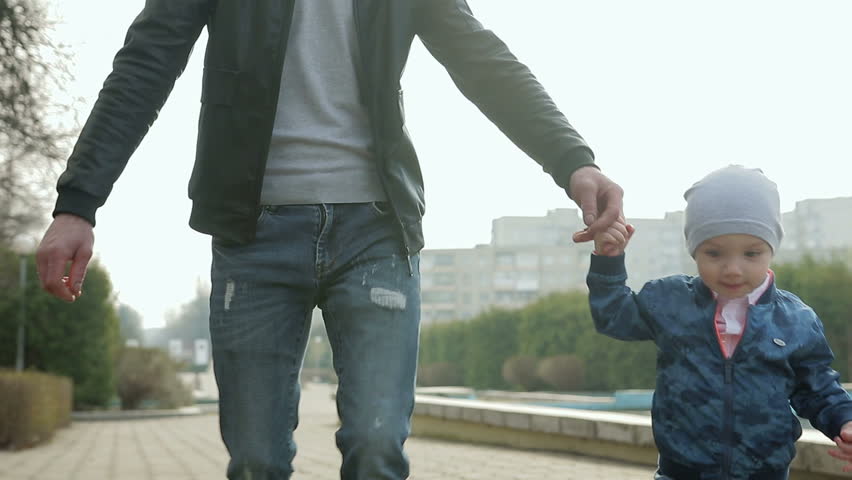 Funny little boy 1-2 years runs next to dad, holding dad