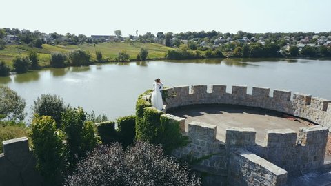 Beautiful romantic wedding couple of newlyweds hugging in an old castle. Aerial view: stockvideo