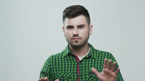 Young man in green shirt, showing by hands enough! Handling the cross. Copy space, isolated gray studio background.