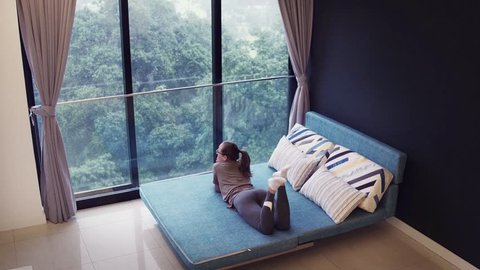 Young woman lying on the sofa at the rent home. Huge panoramic window.